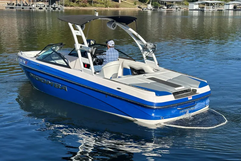 Slide: The Image of 2015 Moomba Mobius LSV boat on a calm lake, featuring a blue and white design. - 63