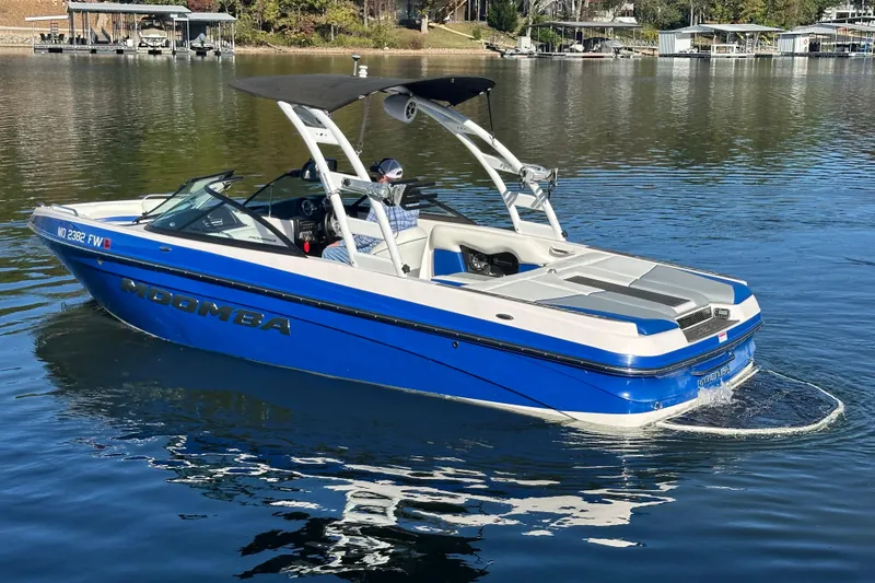 Slide: The Image of 2015 Moomba Mobius LSV boat on a calm lake, featuring a blue and white design. - 65