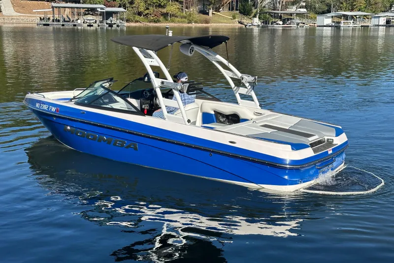 Slide: The Image of 2015 Moomba Mobius LSV boat on a calm lake, surrounded by trees and houses. - 66