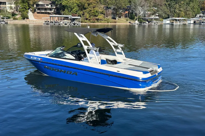 Slide: The Image of 2015 Moomba Mobius LSV boat on a calm lake, surrounded by trees and houses. - 68