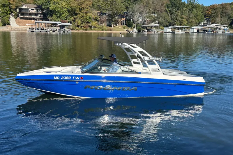 Slide: The Image of 2015 Moomba Mobius LSV boat on a calm lake, featuring a sleek blue design. - 74