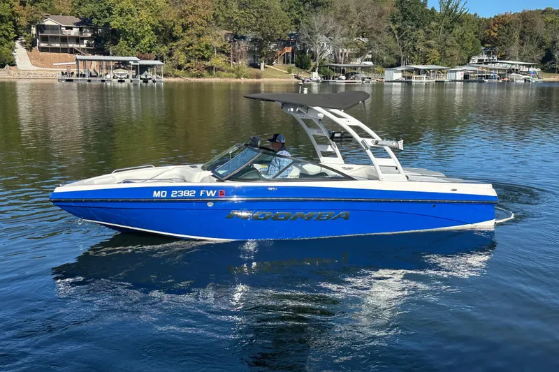 Slide: The Image of 2015 Moomba Mobius LSV boat on a calm lake, featuring a sleek blue design. - 75