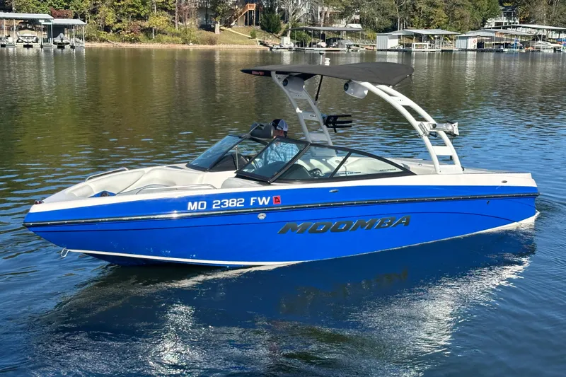 Slide: The Image of 2015 Moomba Mobius LSV boat on a calm lake, featuring a sleek blue design. - 76
