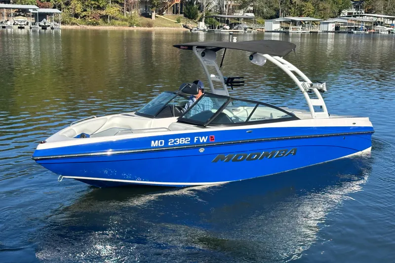 Slide: The Image of 2015 Moomba Mobius LSV boat on a calm lake, featuring a sleek blue design. - 77