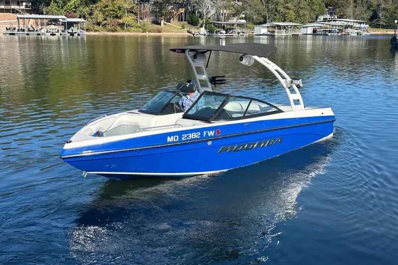Slide: The Image of 2015 Moomba Mobius LSV boat cruising on a serene lake with scenic background. - 78