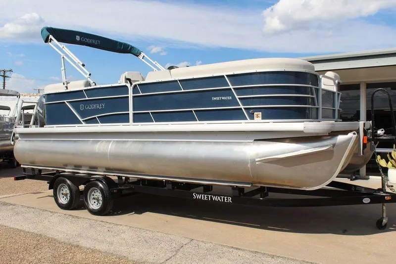 The Image of 2023 Godfrey Sweetwater 2286 C Sport Tube pontoon boat on trailer, blue and silver design. - 1