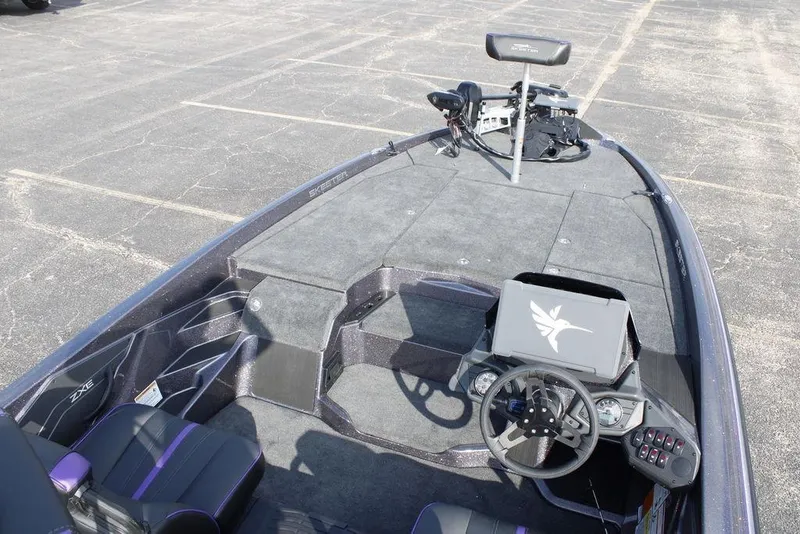 Slide: The Image of 2026 Skeeter ZXE20 boat interior with steering wheel and seating, parked on asphalt. - 22