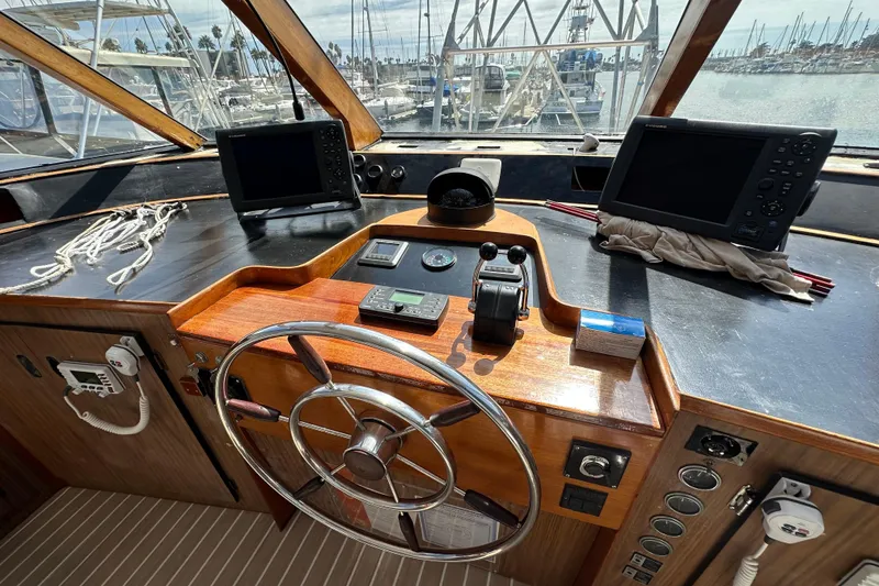 Slide: The Image of 1973 Elliott Yachtfisher interior with white seating, helm chairs, and marina view. - 16