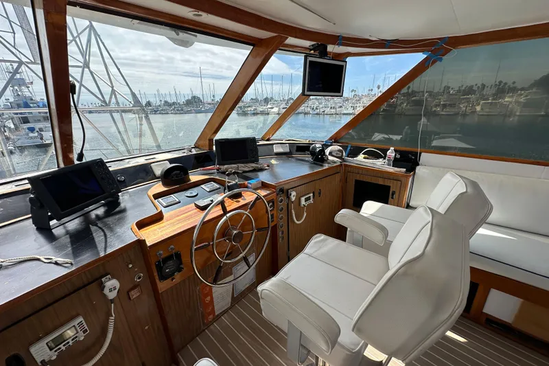 Slide: The Image of 1973 Elliott Yachtfisher helm with steering wheel, navigation equipment, and marina view. - 18