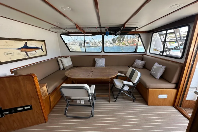 Slide: The Image of Interior of a 1973 Elliott Yachtfisher with white seating and helm, overlooking marina. - 24