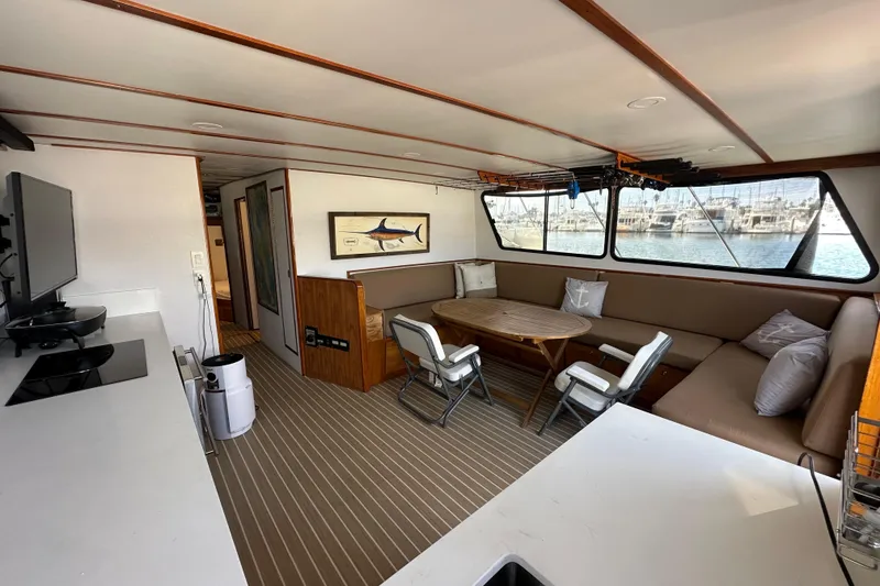 Slide: The Image of 1973 Elliott Yachtfisher interior with seating, table, kitchenette, and waterfront view. - 31
