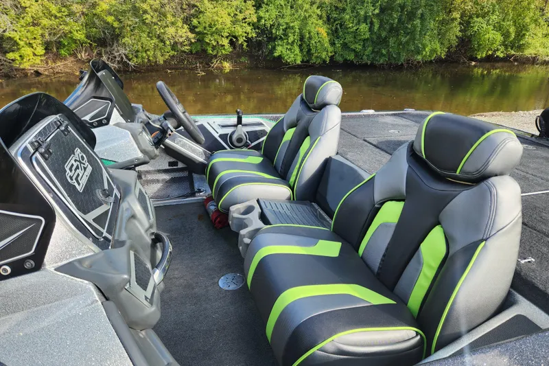 Slide: The Image of 2019 Skeeter FX21 boat interior with green and black seats, near a wooded shoreline. - 14