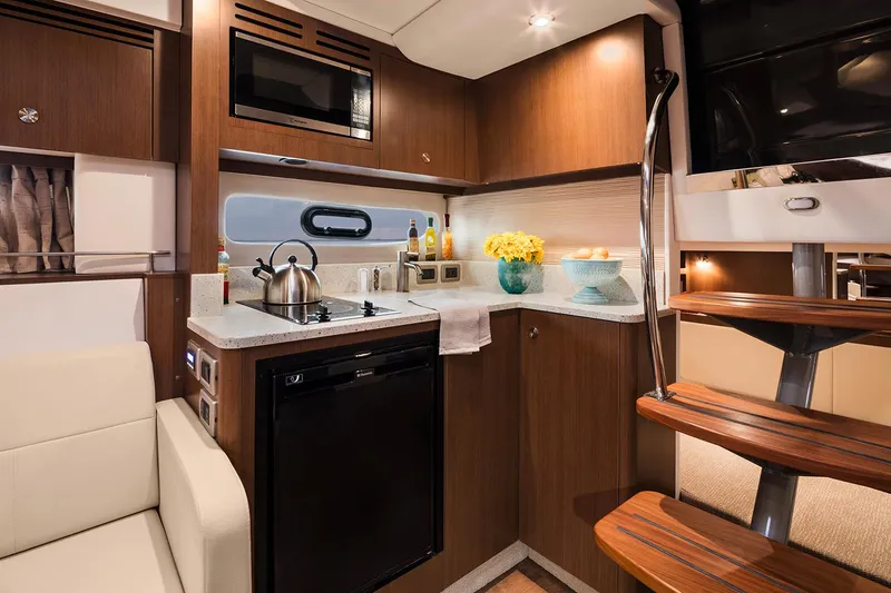 Slide: The Image of 2018 Sea Ray Sundancer 350 yacht interior kitchen with modern appliances and wooden cabinetry. - 11