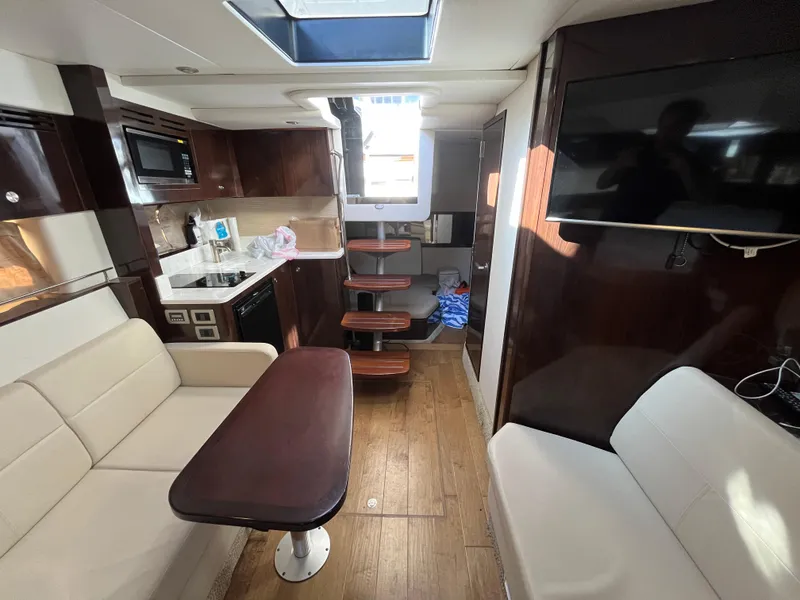 Slide: The Image of 2018 Sea Ray Sundancer 350 interior with modern kitchen, seating, and wooden flooring. - 26