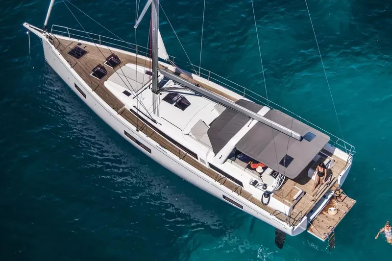 Slide: The Image of 2026 Beneteau Oceanis Yacht 54 sailing on clear blue waters, aerial view. - 2