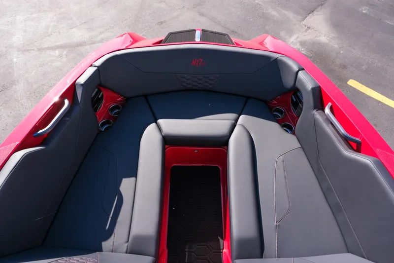 Slide: The Image of 2026 MasterCraft NXT22 boat interior with red and gray seating, cup holders, and sleek design. - 20
