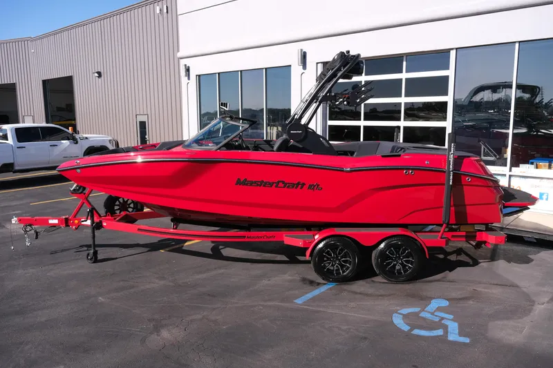 Slide: The Image of 2026 MasterCraft NXT22 boat in vibrant red on a trailer, parked outside a building. - 31