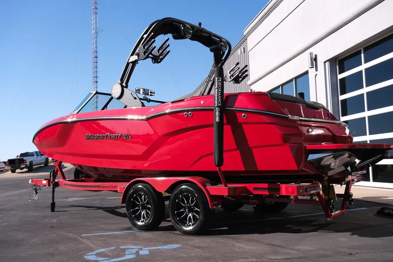 Slide: The Image of 2026 MasterCraft NXT22 boat in vibrant red on a trailer, parked outdoors. - 32