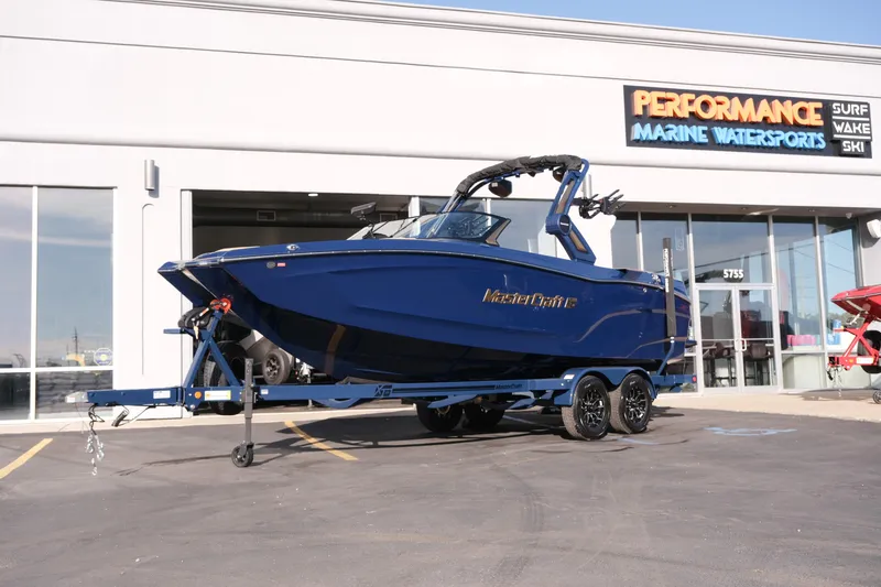 Slide: The Image of 2026 MasterCraft XT22 boat on trailer outside Performance Marine Watersports store. - 25