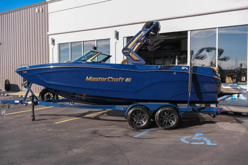 Slide: The Image of 2026 MasterCraft XT22 boat in blue on a trailer outside a building. - 27