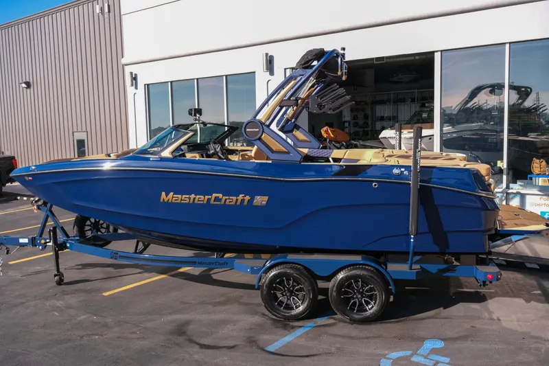 Slide: The Image of 2026 MasterCraft XT22 boat in blue, parked on a trailer outside a showroom. - 4