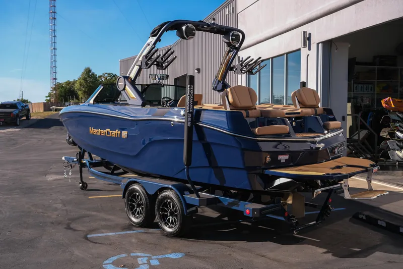 Slide: The Image of 2026 MasterCraft XT22 boat in blue, parked on a trailer outside a building. - 6