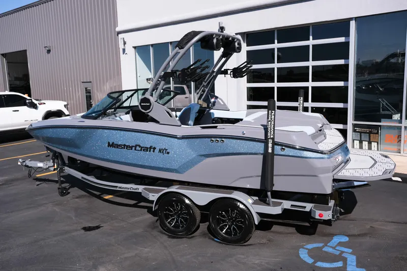 Slide: The Image of 2026 MasterCraft NXT20 boat on trailer, parked outside a showroom. - 19
