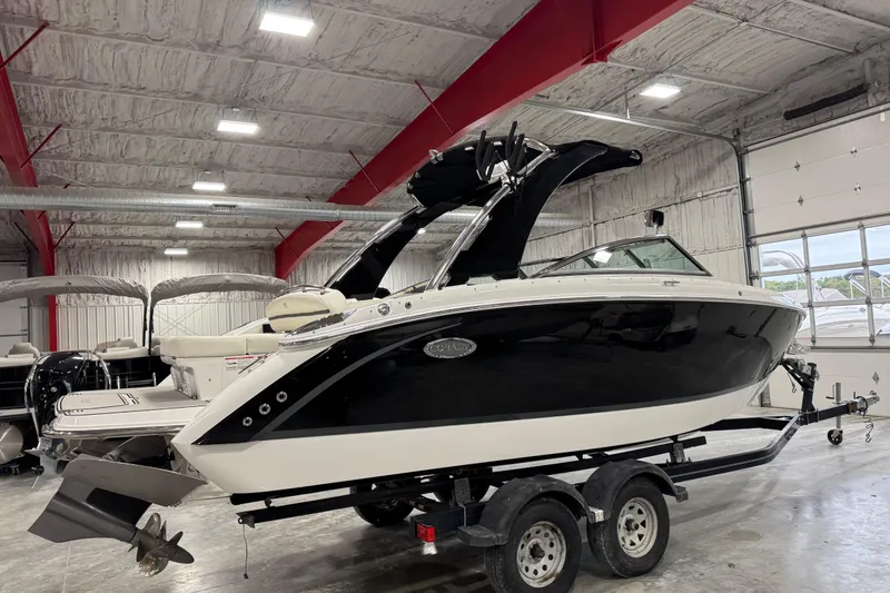 Slide: The Image of 2018 Cobalt R5 Surf boat in indoor storage, black and white design, on a trailer. - 3