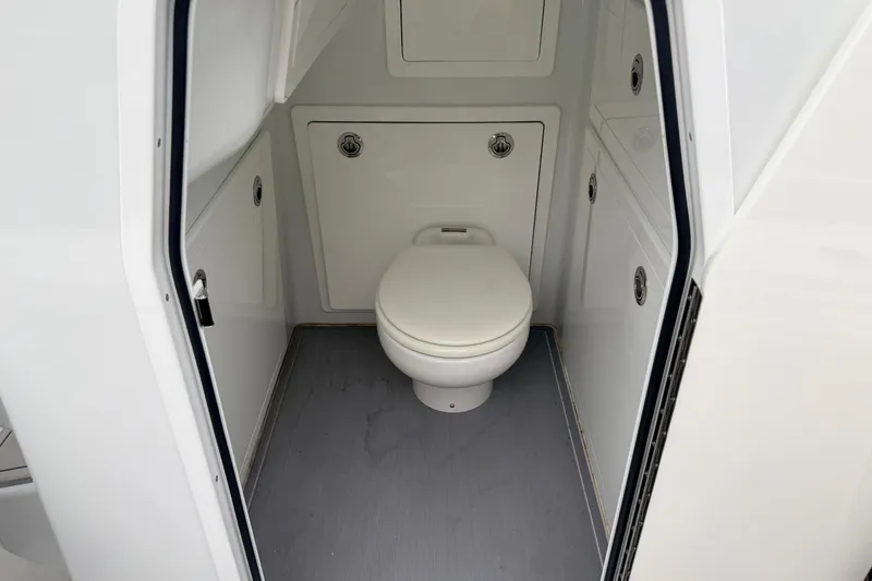 Slide: The Image of Interior view of 2022 Costa Custom Boats 264 bathroom with white toilet and storage compartments. - 23