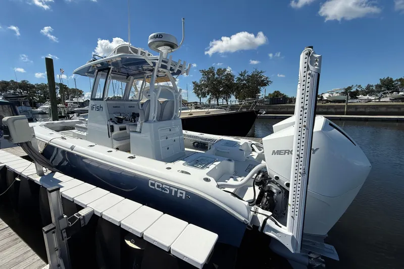 Slide: The Image of 2022 Costa Custom Boats 264 docked, featuring Mercury engine, clear sky background. - 28