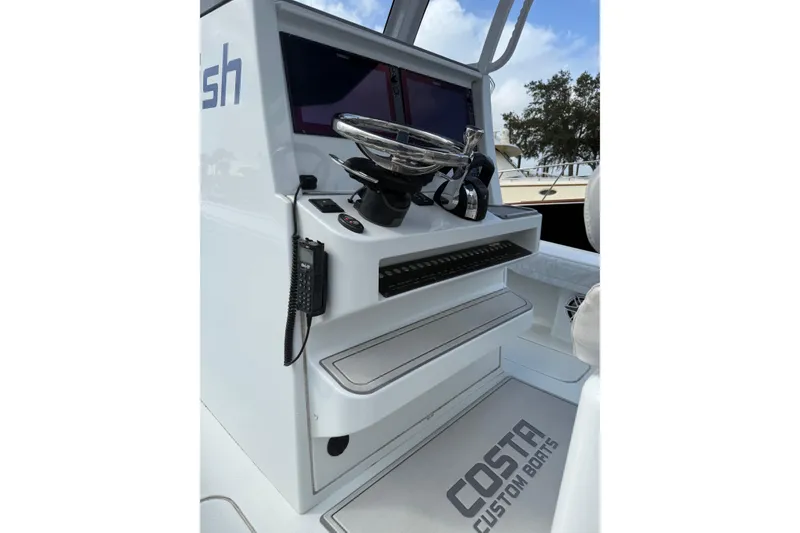 Slide: The Image of 2022 Costa Custom Boats 264 dashboard with steering wheel and controls. - 33