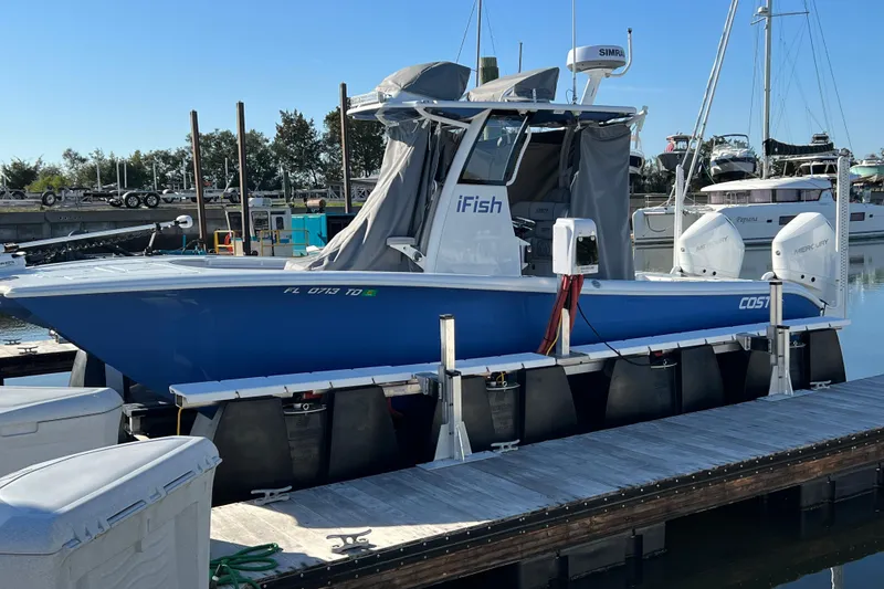 Slide: The Image of 2022 Costa Custom Boats 264 docked, featuring blue hull and twin Mercury engines. - 36