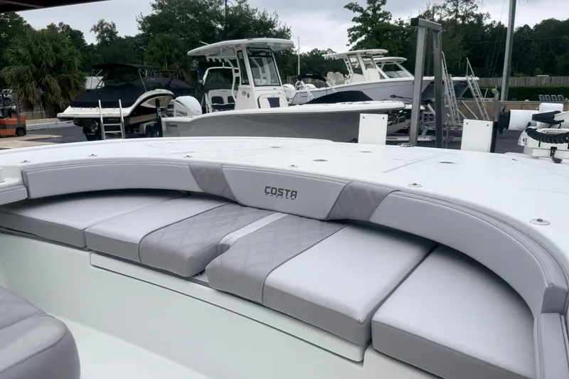 Slide: The Image of 2022 Costa Custom Boats 264 with cushioned seating, docked among other boats. - 7