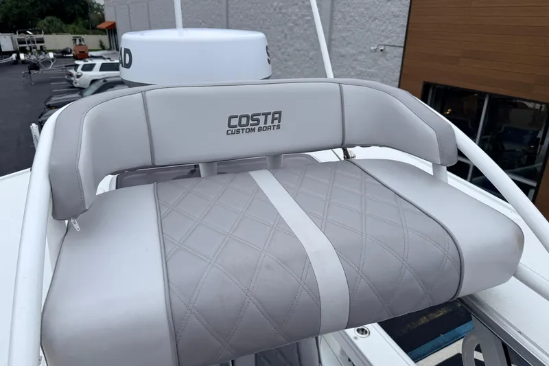 Slide: The Image of Gray cushioned seat on 2022 Costa Custom Boats 264, featuring diamond stitching and logo. - 9