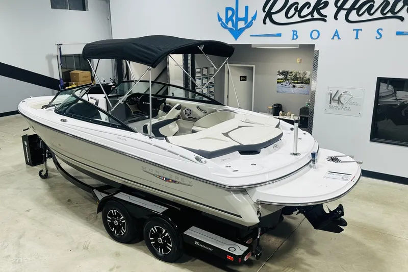 Slide: The Image of 2025 Monterey 224FS boat with black canopy in showroom, Rock Hard Boats logo visible. - 4