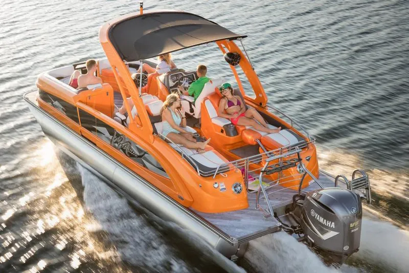 Slide: The Image of 2018 Manitou 25 X-Plode XT RFX pontoon boat with Evinrude motor, parked on grass. - 0