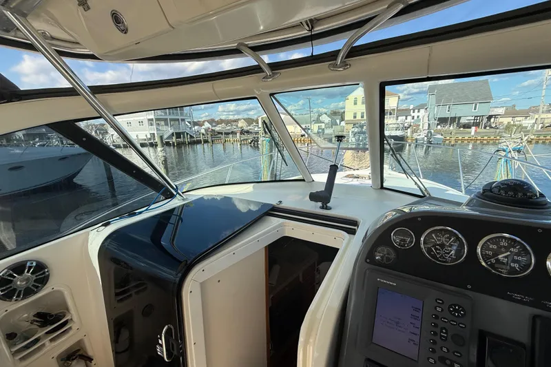 Slide: The Image of 2004 Pursuit 3100 Offshore boat interior with navigation controls and marina view. - 14
