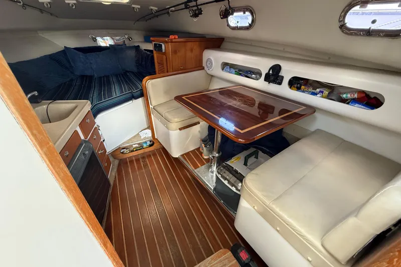 Slide: The Image of 2004 Pursuit 3100 Offshore cabin interior with seating, table, and kitchenette. - 17