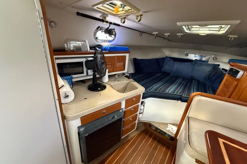 Slide: The Image of 2004 Pursuit 3100 Offshore cabin interior with kitchenette and cozy seating area. - 18