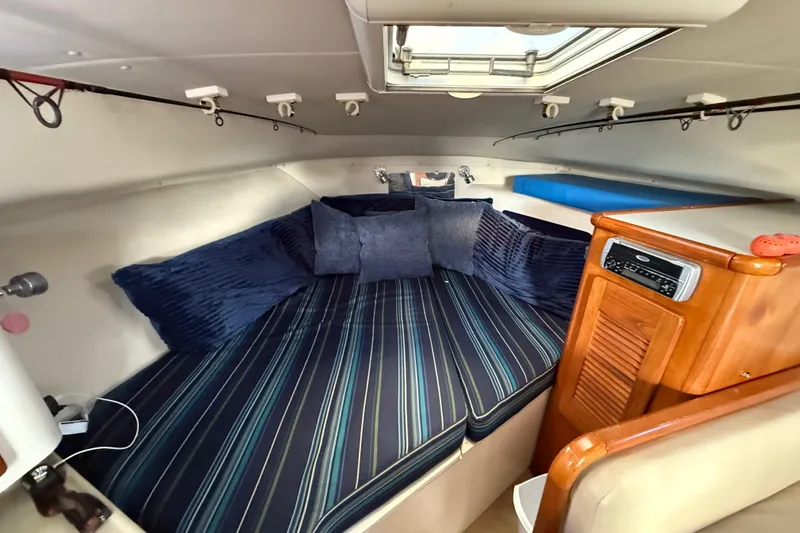 Slide: The Image of Interior of 2004 Pursuit 3100 Offshore boat with cozy cabin and striped bedding. - 21