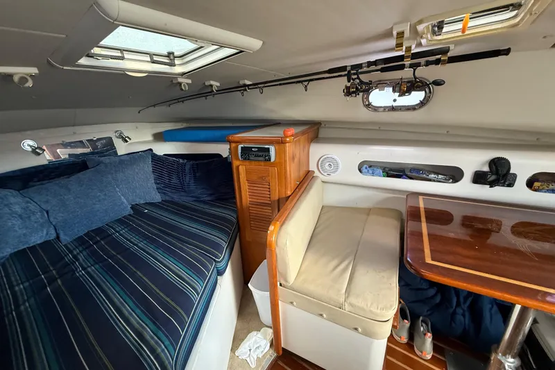 Slide: The Image of Interior of 2004 Pursuit 3100 Offshore boat with seating, table, and fishing rod storage. - 22