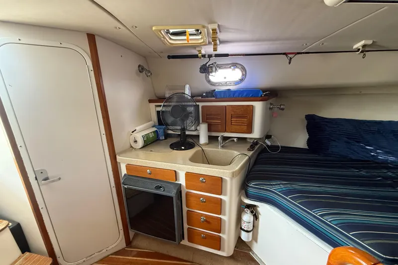 Slide: The Image of 2004 Pursuit 3100 Offshore cabin with bed, sink, and storage drawers. - 23