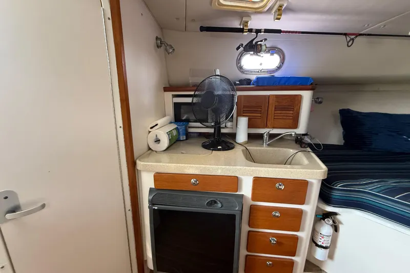 Slide: The Image of 2004 Pursuit 3100 Offshore cabin with kitchenette, sink, and bed. - 24