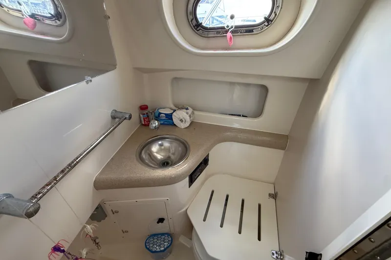 Slide: The Image of 2004 Pursuit 3100 Offshore boat bathroom with sink, window, and storage. - 25