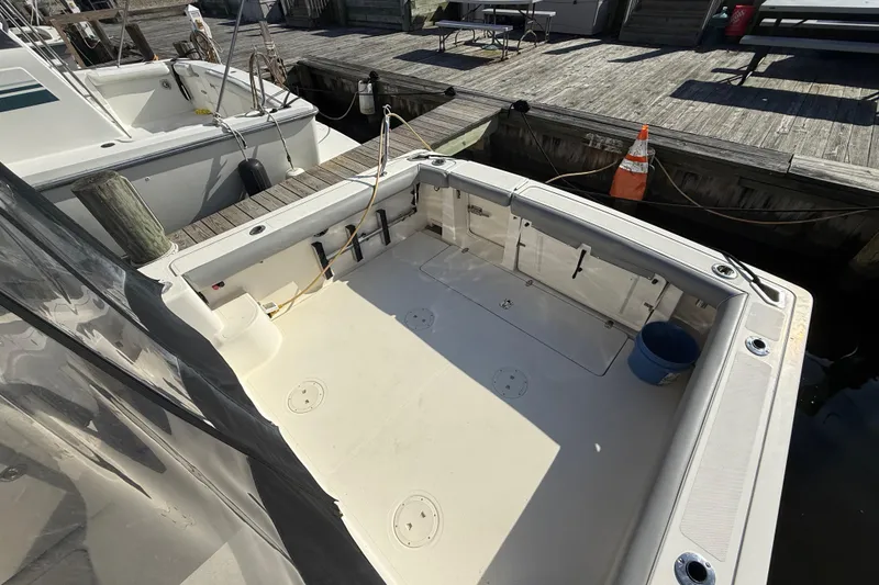 Slide: The Image of 2004 Pursuit 3100 Offshore boat deck at dock, featuring spacious layout and fishing equipment. - 7