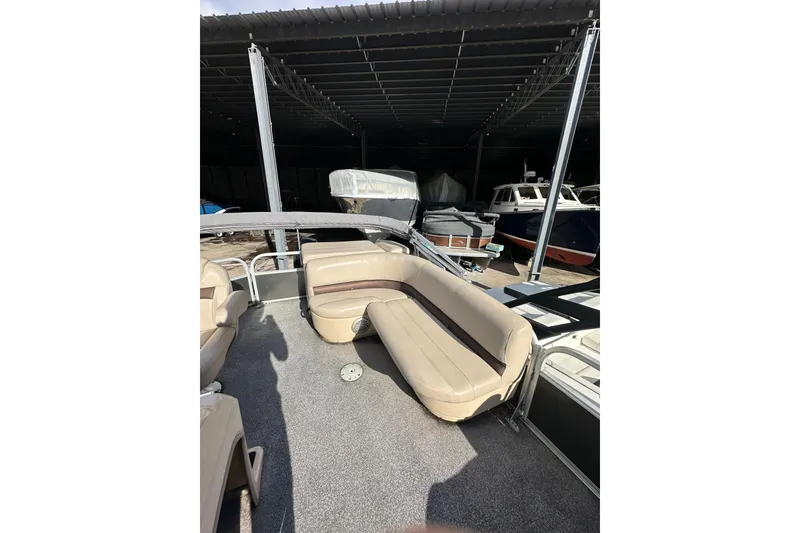 Slide: The Image of 2017 Sun Tracker Party Barge 20 DLX with beige seating in a covered marina. - 12