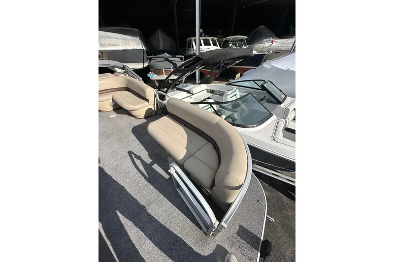 Slide: The Image of 2017 Sun Tracker Party Barge 20 DLX pontoon boat with beige seating, docked among other boats. - 9