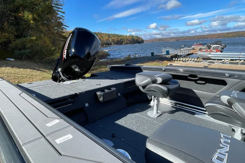 Slide: The Image of 2026 Lund 1875 Crossover XS boat interior with Mercury engine by a scenic lake. - 12