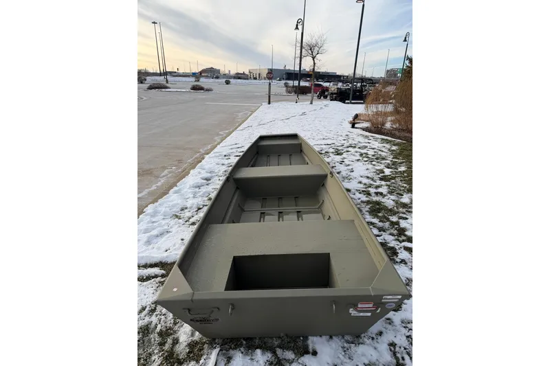 Slide: The Image of 2026 Tracker Grizzly 14 Jon boat on snowy ground, showcasing its sturdy design. - 2