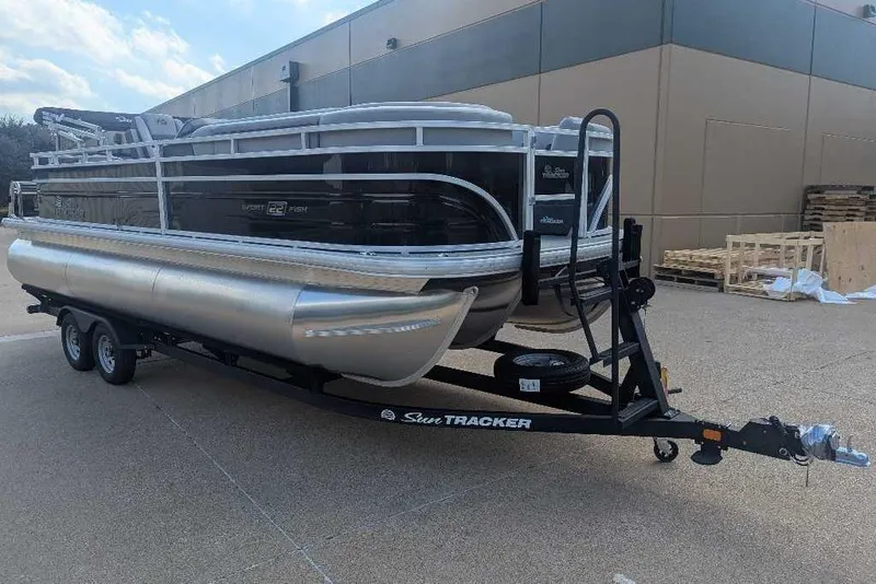 Slide: The Image of 2026 Sun Tracker SportFish 22 XP3 pontoon boat on trailer, parked outdoors. - 6